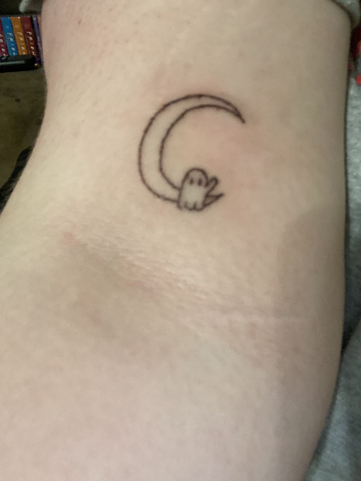 a small skull and crescent tattoo on the back of a woman's leg,