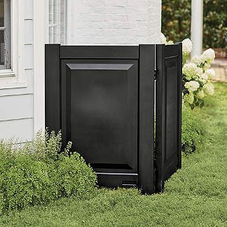 a black trash can sitting in the grass next to a house