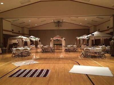 an indoor basketball court with tables and chairs set up for a formal function in the center