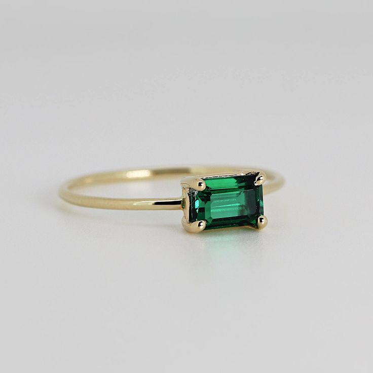 This beautiful East West Emerald Gold Ring was handmade in Melt'm Jewelry Design Studio in California using 14k solid yellow gold band and 6x4mm emerald cut lab grown emerald stone. Emerald is featuring in 14k gold prong setting. DETAILS ABOUT THE RING, MATERIAL AND STONES Ring Band: 14K solid gold Ring Band size: 1.2 mm thick Gemstone: Lab grown Emerald Emerald size: 6mm x 4mm emerald cut Yellow gold or white gold options available from drop down menu. It is a great birthday gift for your speci East West Emerald Ring, Emerald Cut Emerald Ring, Emerald Gold Ring, Jewelry Design Studio, May Birthstone Rings, Minimalist Engagement Ring, Emerald Engagement, Gold Band Ring, Solid Gold Rings