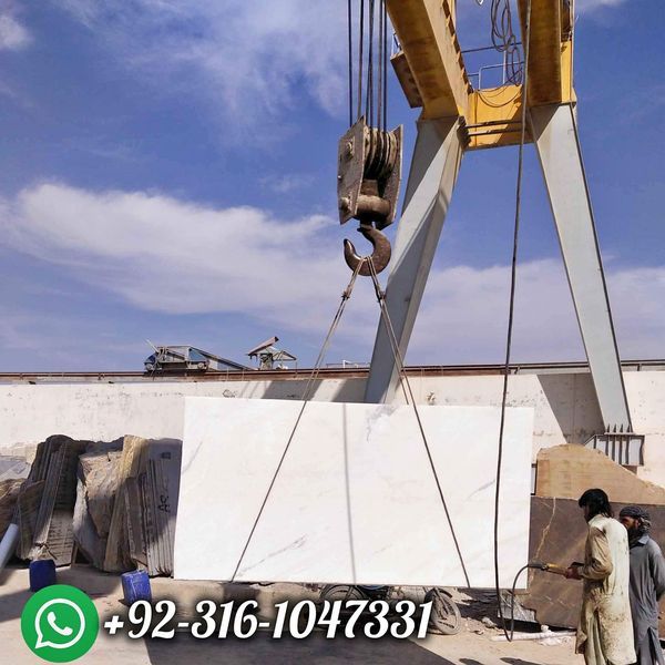 two men working on a large crane in the middle of a construction area with blue sky and clouds