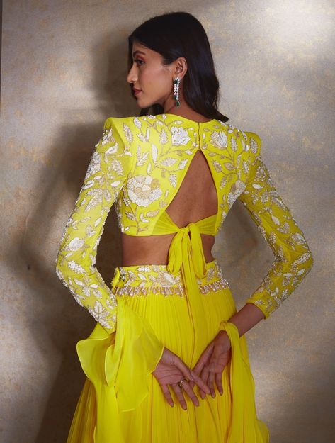 The Ellen ensemble features a vibrant yellow crop top with a powerful shoulder detailing and ivory camellia flowers. It is styled with a tiered georgette lehenga featuring an embellished waistband. Complete with a modest ruffle dupatta. Color customization available. Floor-length Ruffled Georgette Choli, Georgette Lehenga With Ruffles For Reception, Elegant Georgette Anarkali Set With Ruffles, Reception Georgette Lehenga With Ruffles, Reception Lehenga With Ruffles In Georgette, Party Wear Choli With Ruffles For Reception, Ruffled Choli For Party Wear, Ruffled Choli For Reception Party Wear, Yellow Ruffled Wedding Sets