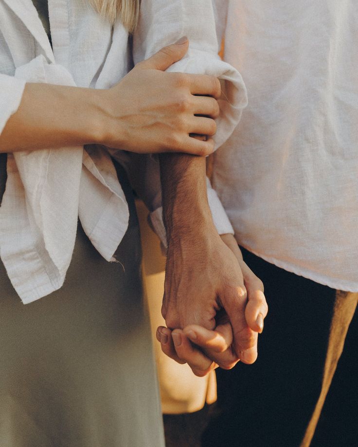 two people holding hands while standing next to each other