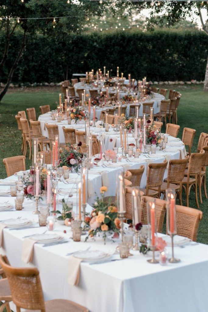 a long table is set with candles and flowers for an outdoor wedding reception in the garden