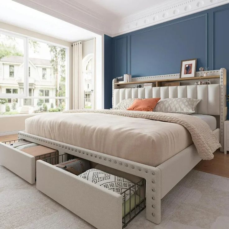 a bedroom with blue walls and white bedding has drawers under the headboard for storage