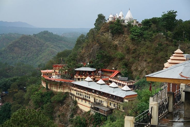 a large building sitting on top of a mountain next to a lush green forest covered hillside