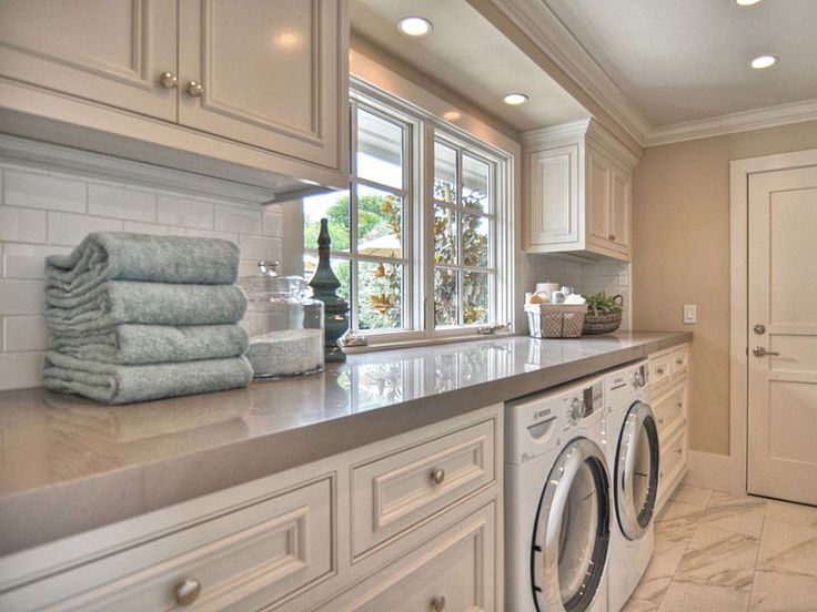 a washer and dryer in a room with white cabinets on the counter top