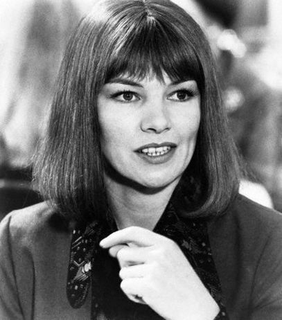 an old photo of a woman with long hair wearing a suit and tie, looking at the camera