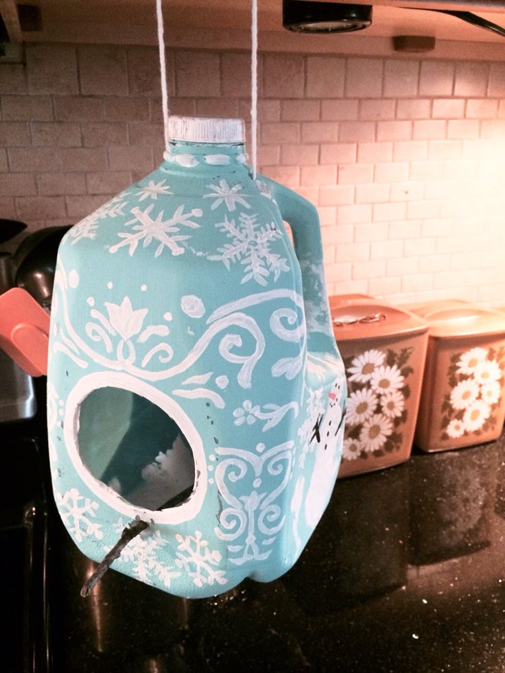 a blue birdhouse hanging from a kitchen counter with white snowflakes on it