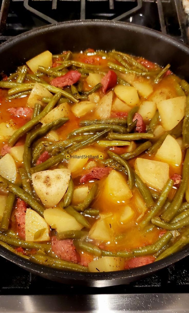 potatoes and green beans are cooking in a skillet on the stove top with sauce