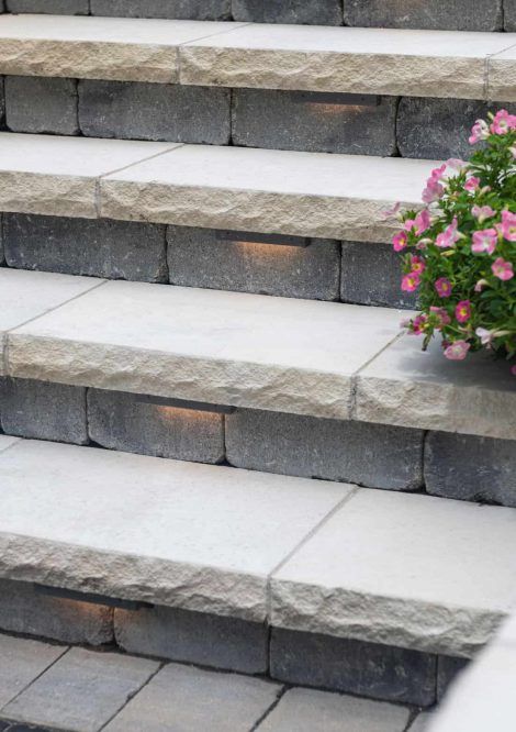 a planter with pink flowers sitting on top of stone steps next to some stairs