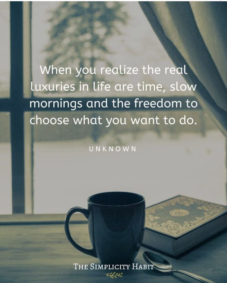 a coffee cup sitting on top of a table next to a book and a spoon