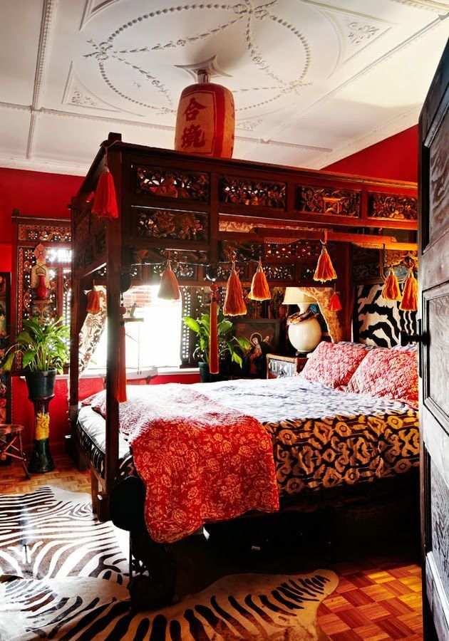 a bedroom with red walls, zebra print rugs and a canopy bed in the middle