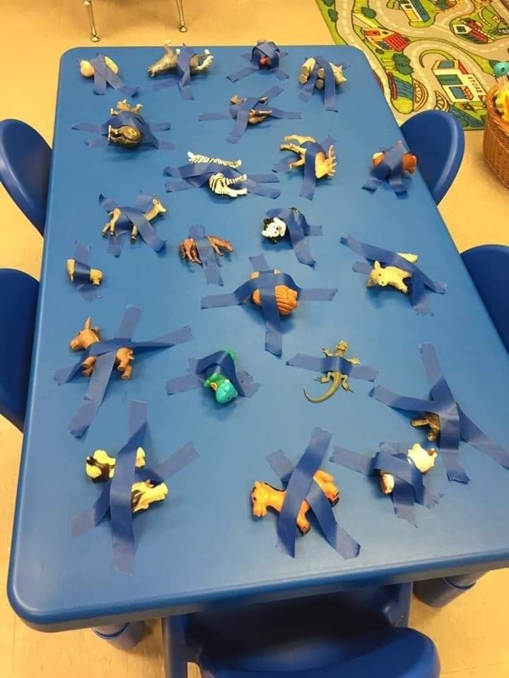 a blue table topped with lots of small toy animals on top of plastic chairs next to each other