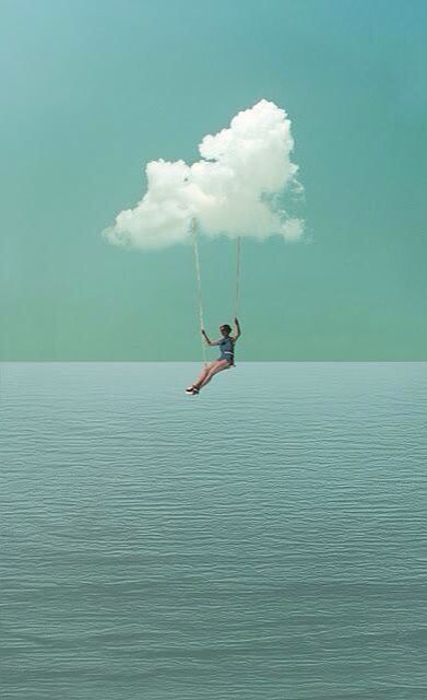 a person hanging from a cloud over the ocean