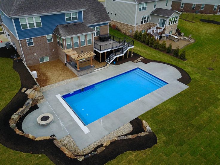 an aerial view of a backyard with a swimming pool and patio area in the foreground