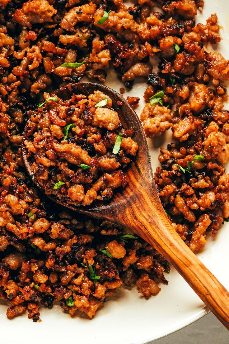 a wooden spoon sitting on top of a plate filled with food