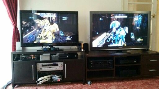 two televisions sitting next to each other on top of a wooden entertainment center in a living room