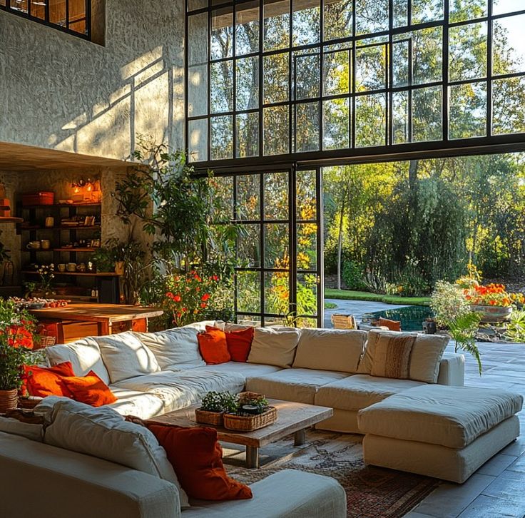 a living room filled with lots of furniture next to a large open window covered in plants