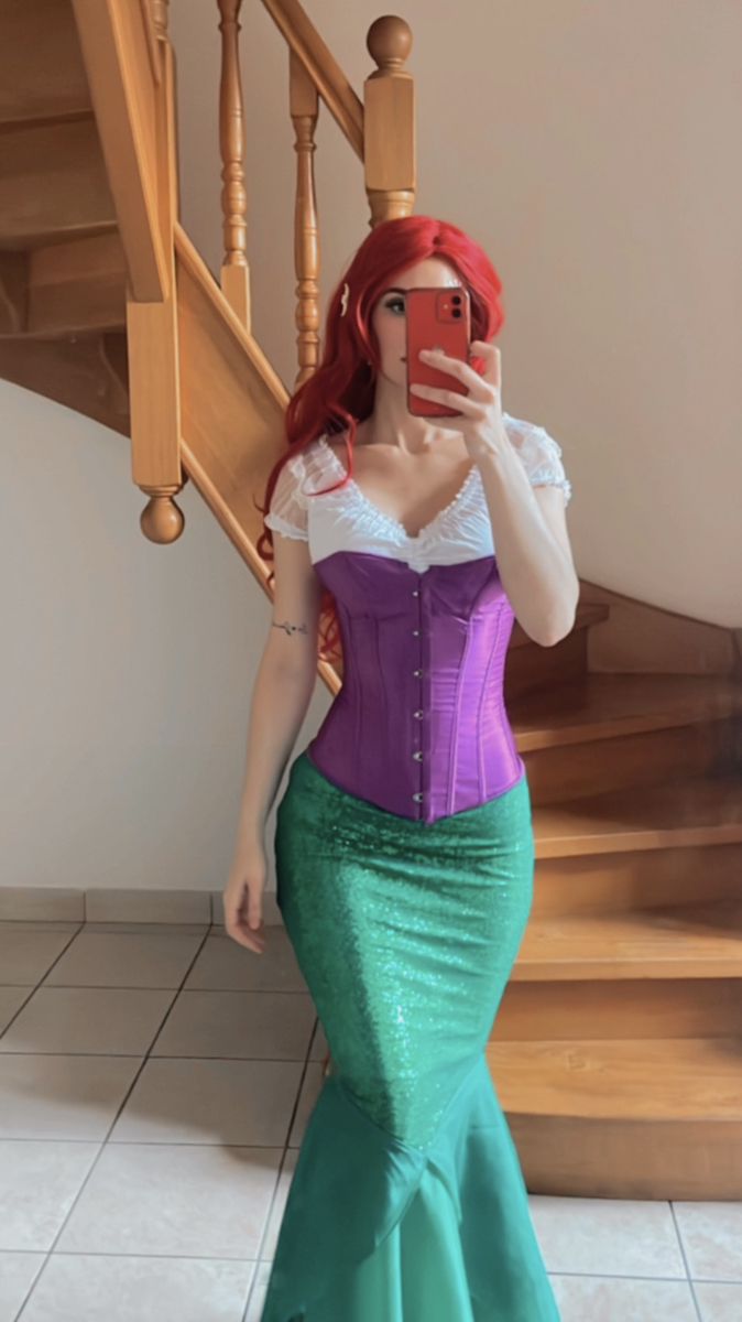 a woman in a green and purple corset taking a selfie with her cell phone