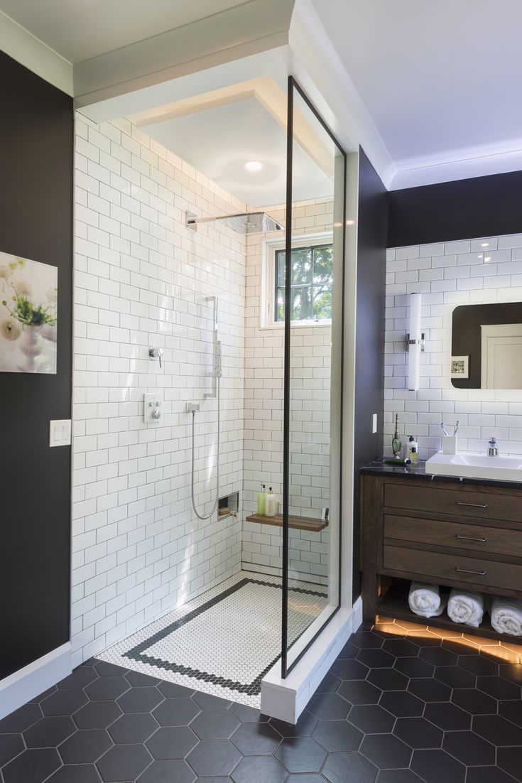 a bathroom with a walk in shower next to a sink and mirror on the wall