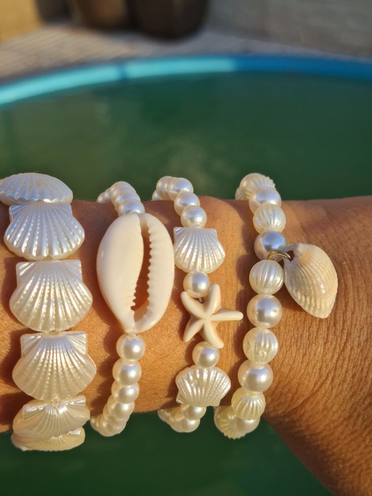 a woman's arm with seashells and pearls bracelets on top of it