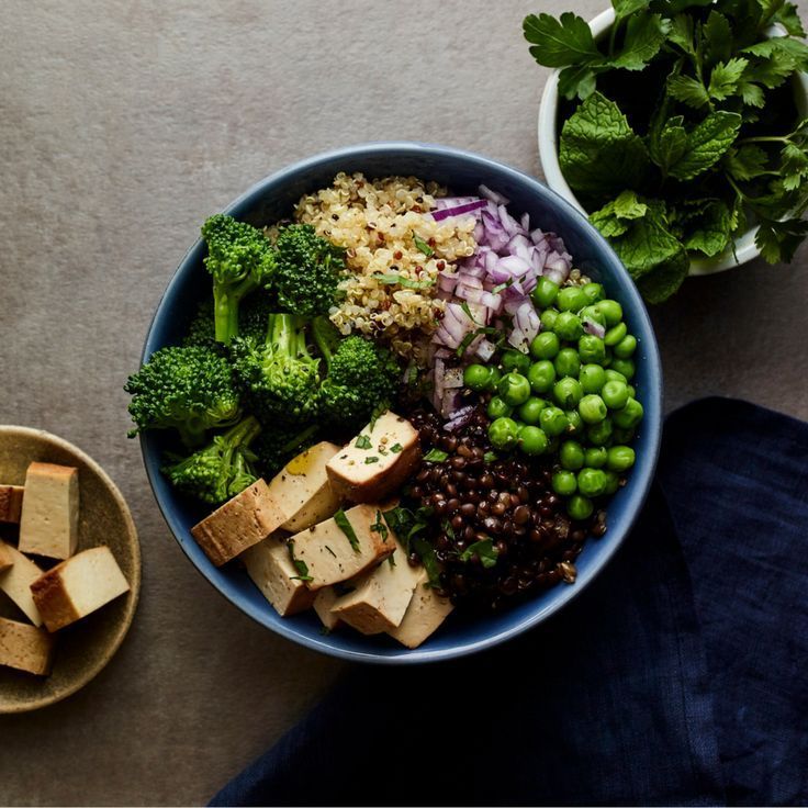 a bowl filled with vegetables and tofu on top of a table