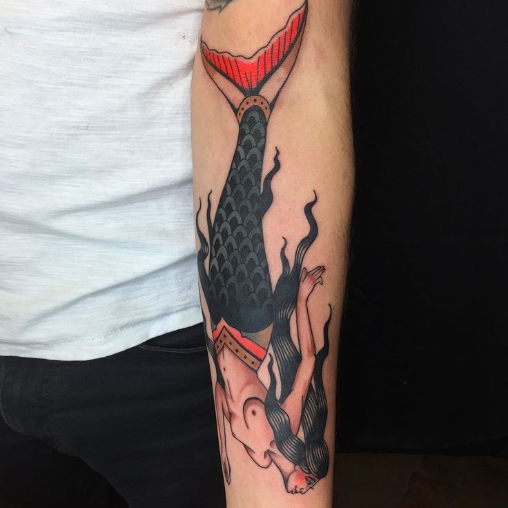 a man with a tattoo on his arm has a black and red fish in the shape of a hourglass