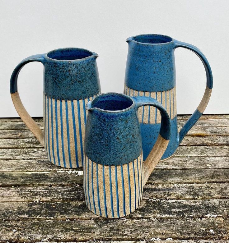 two blue and white striped pitchers sitting on top of a wooden table