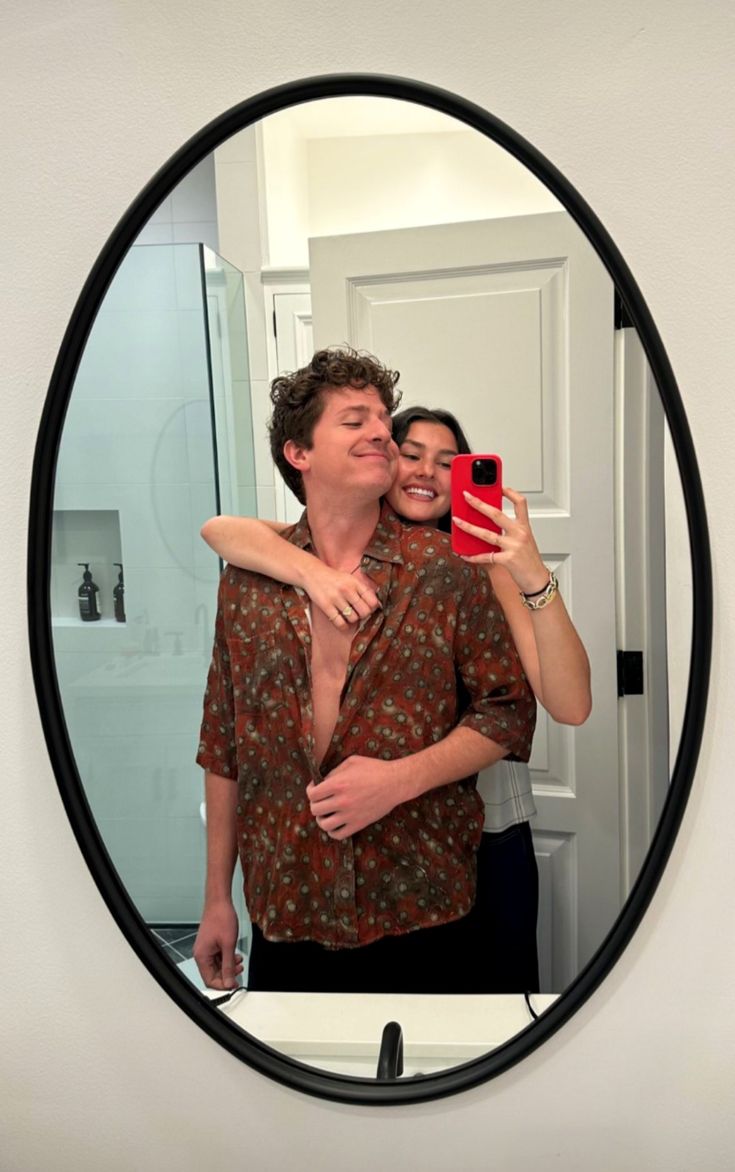 a man and woman taking a selfie in the mirror