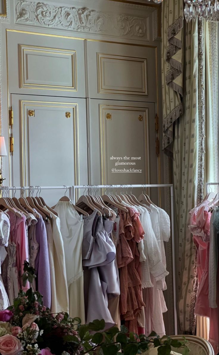 there are many dresses hanging on the rack in this room with chandelier and flowers