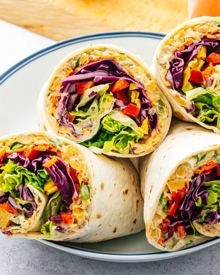 a plate topped with four burritos filled with veggies