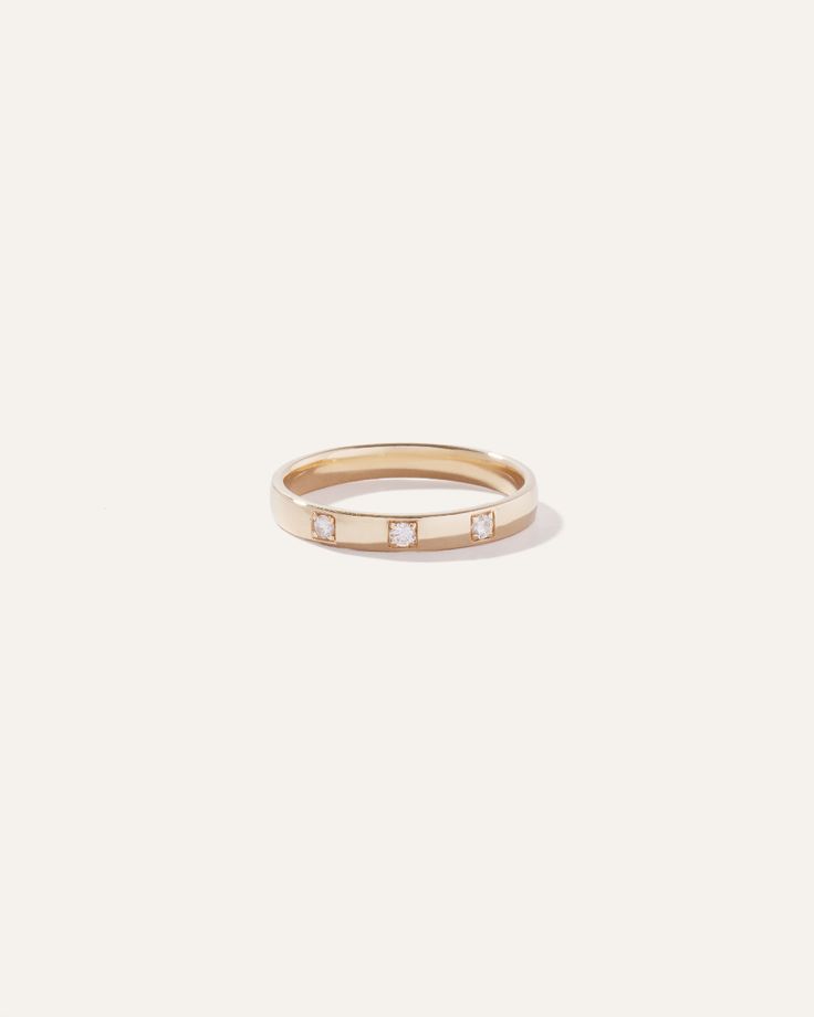 a gold ring with three small diamonds on the front and side, set against a white background