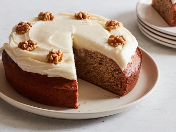 a white plate topped with a cake covered in frosting and walnuts on top of it