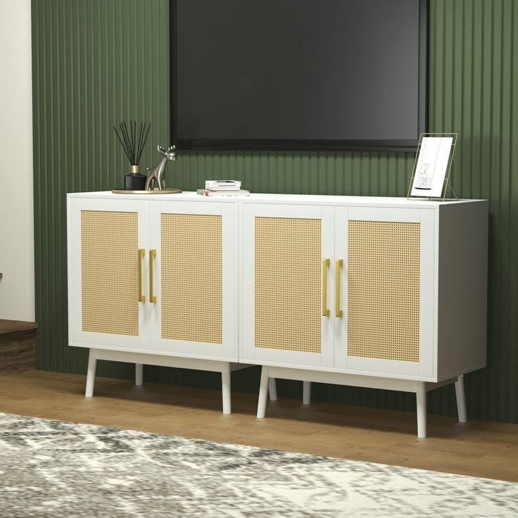 a white cabinet with gold handles in front of a green wall and rug on the floor