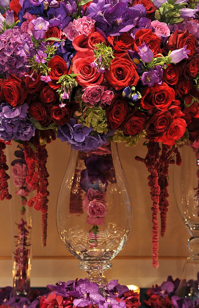 a vase filled with lots of colorful flowers on top of a table next to another vase