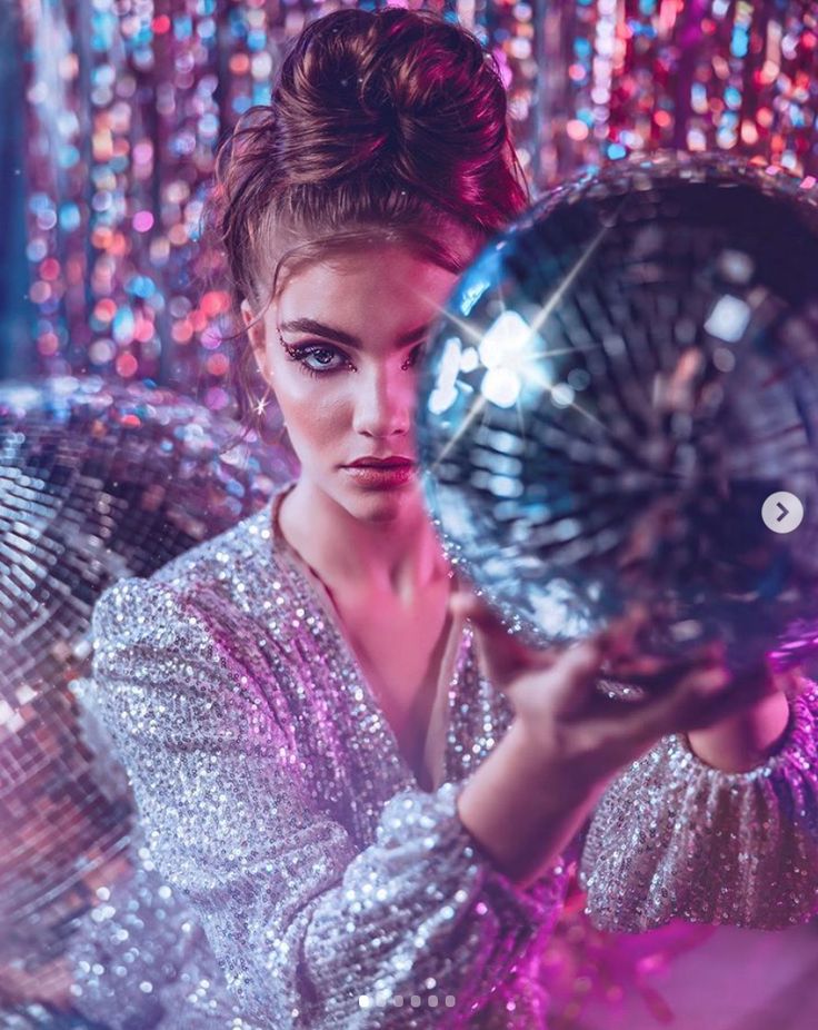 a woman holding a disco ball in front of her face