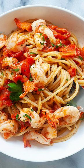 pasta with shrimp and tomato sauce in a white bowl on a marble countertop, ready to be eaten