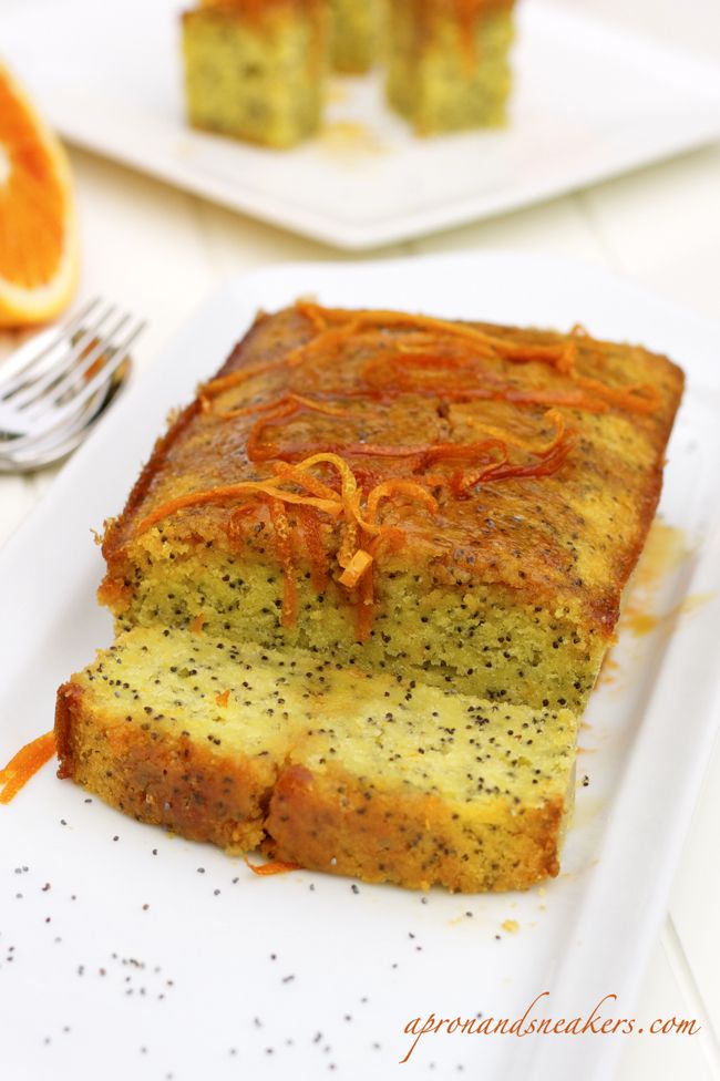 a slice of cake on a plate with oranges and silverware in the background