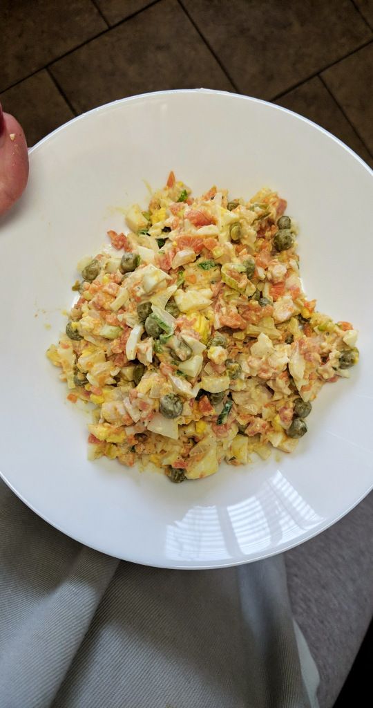 a white plate topped with food on top of a table next to a persons hand