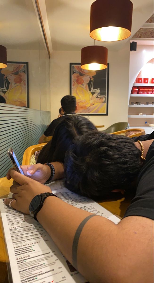 a person sitting at a table with a cell phone in their hand and papers on the desk