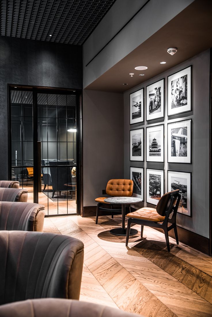 a room with chairs, tables and pictures on the wall in front of glass doors