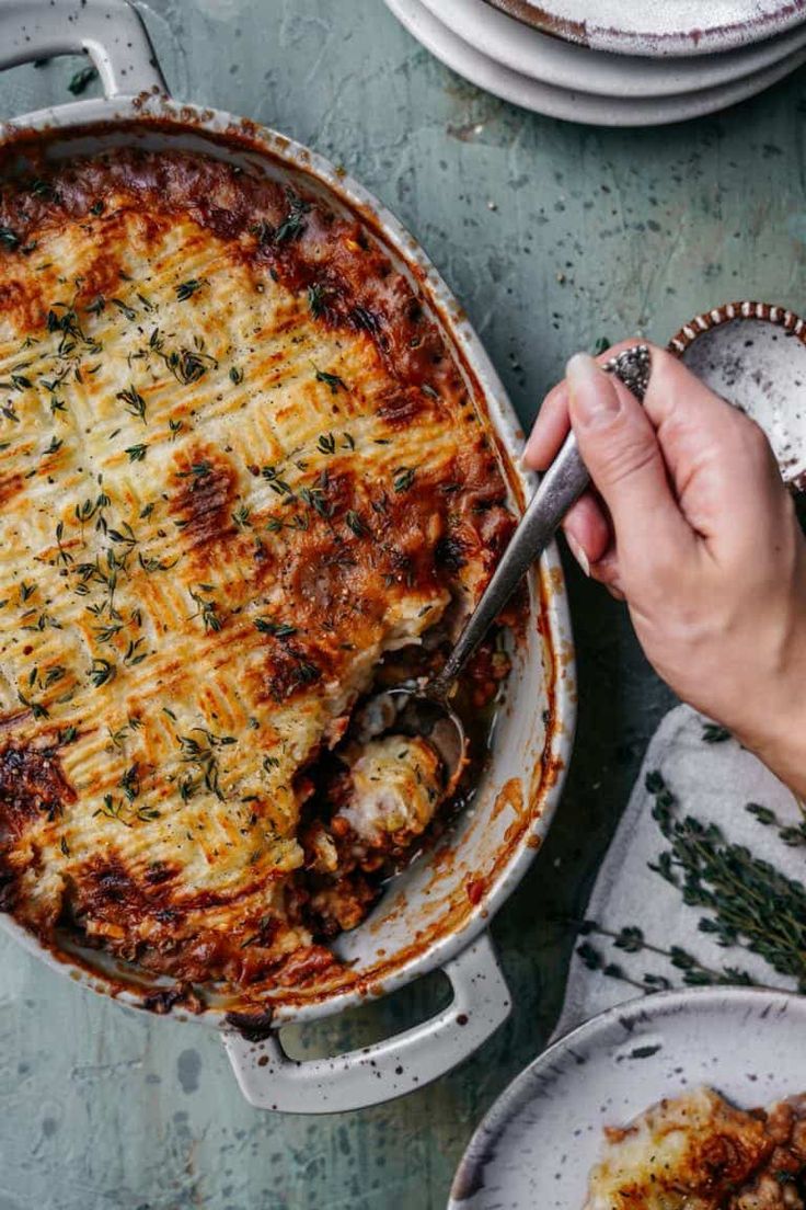 a person holding a spoon in a casserole dish