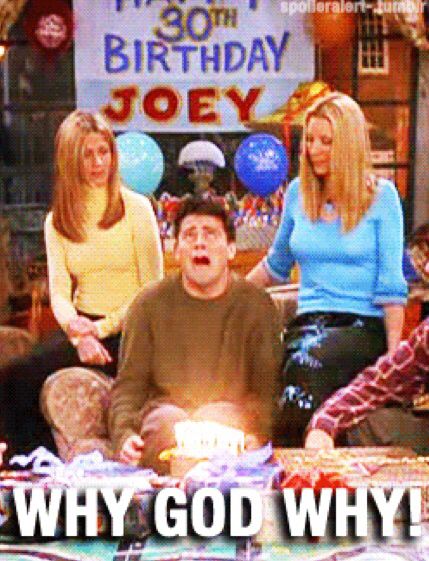 three women and one man sitting in front of a birthday cake