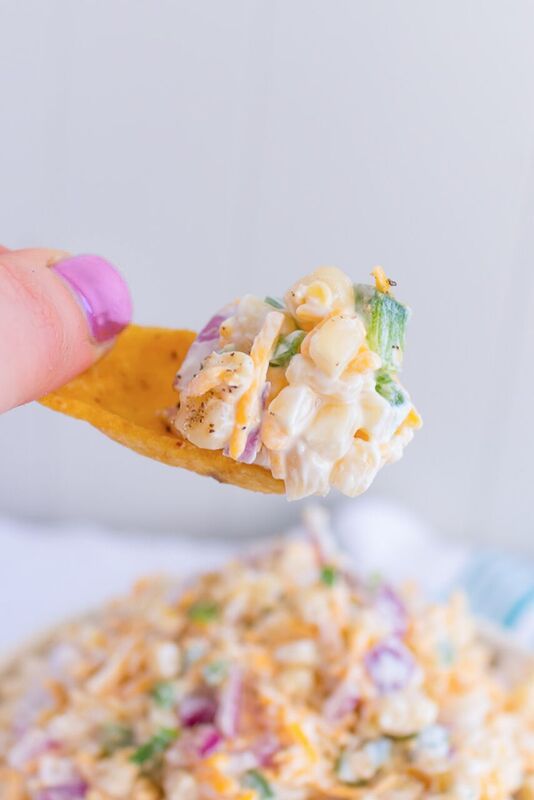 a spoon full of corn dip on top of a white plate with text overlay