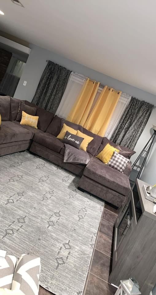 a living room filled with furniture and yellow drapes