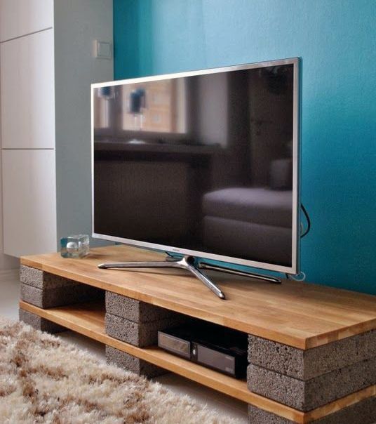 a flat screen tv sitting on top of a wooden stand in front of a blue wall