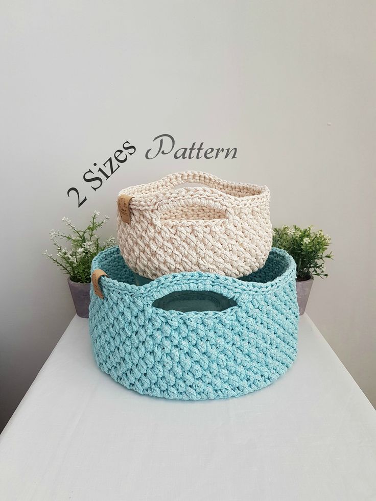 two crocheted storage baskets sitting on top of a white table next to a potted plant