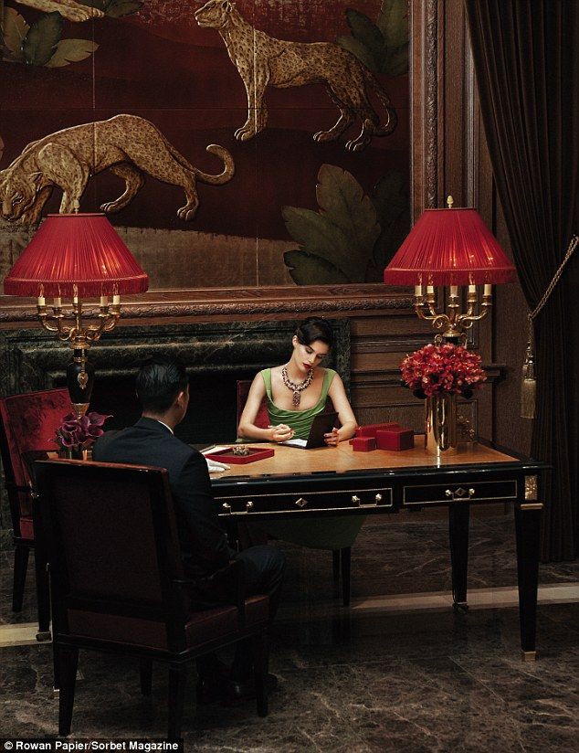 a man and woman sitting at a desk in front of a painting on the wall