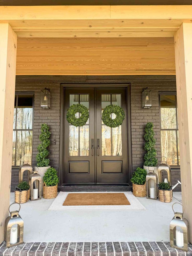 the front door is decorated with wreaths and lanterns